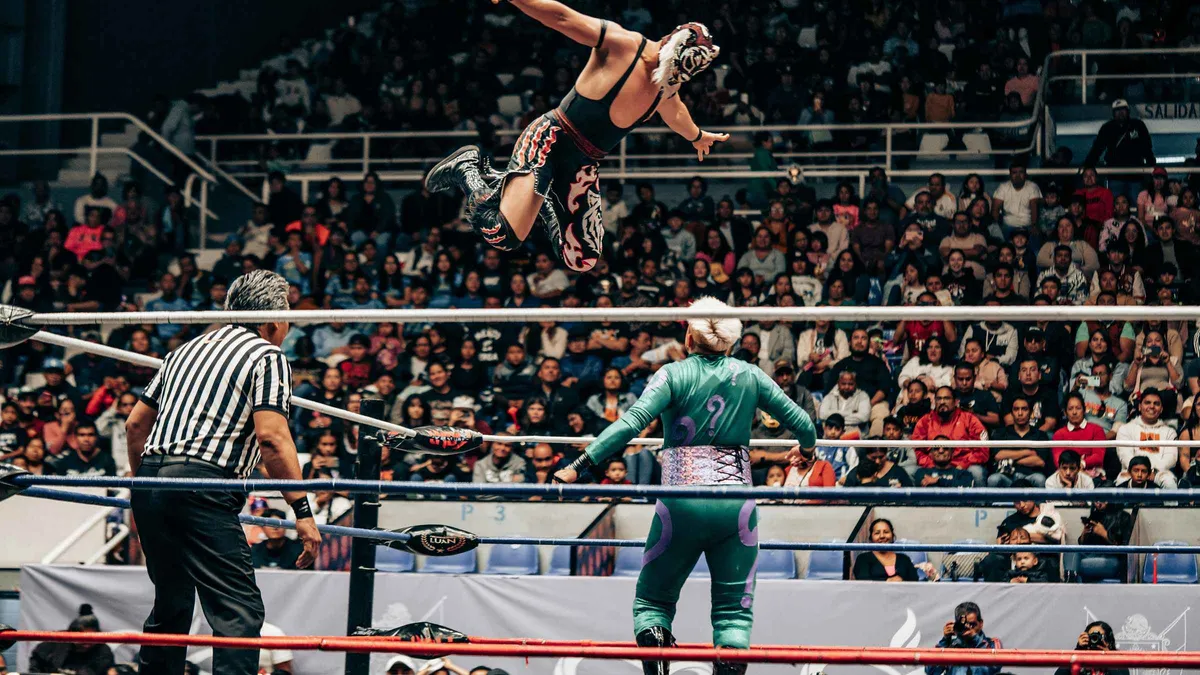 Masked wrestlers mid-flight in the ring at a lucha libre show with tequila tasting in Mexico City