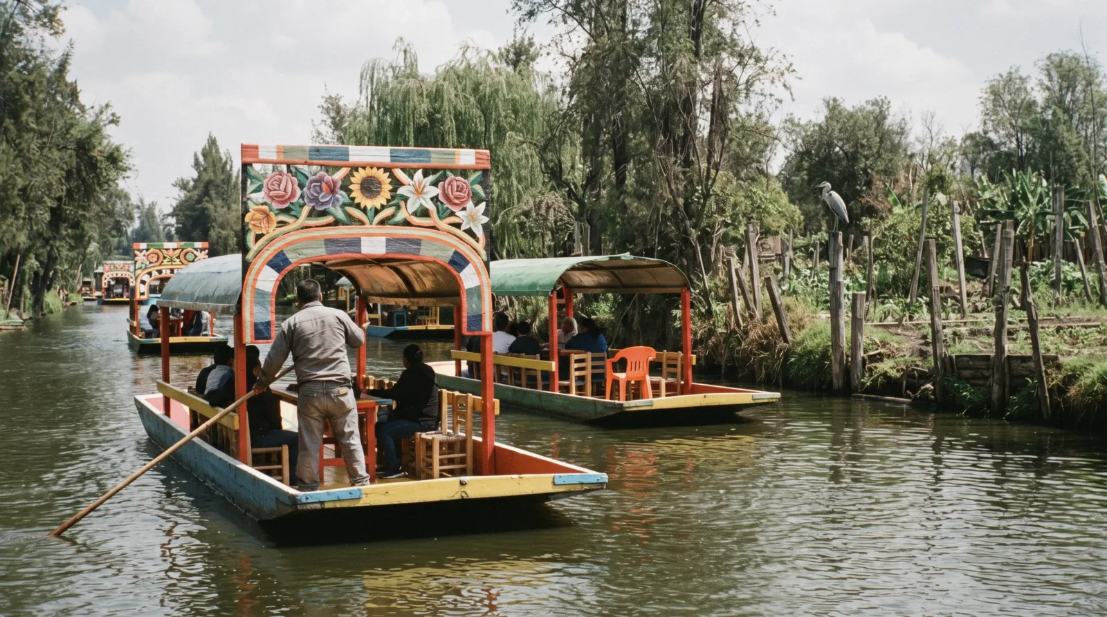 Painted trajinera boats crossing on the canals of Xochimilco under a wide sky, Mexico City